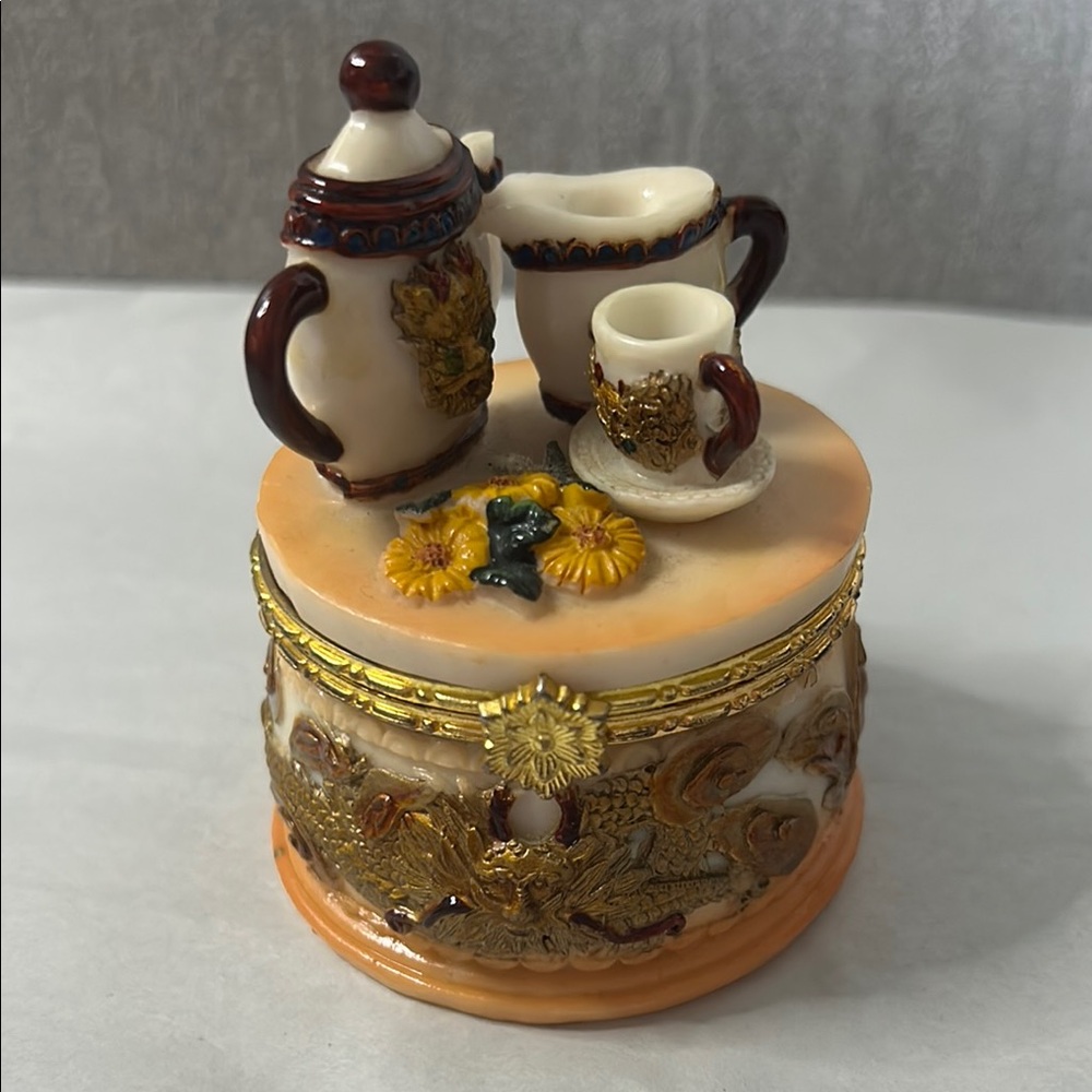 vintage-style hinged trinket box with a tea party theme on the lid.